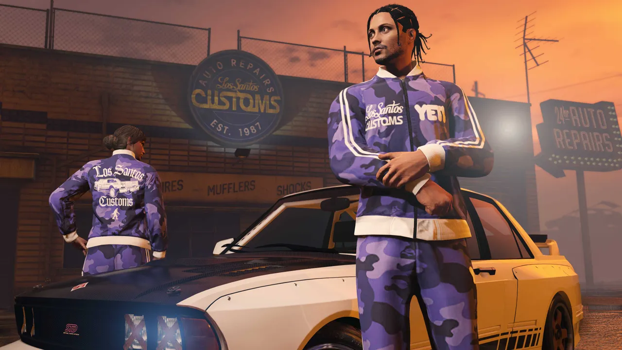 夕暮れのロスサントス・カスタムズの前で、そろいのトラックスーツを着た2人が車の横に立っているGTA Onlineの公式スクリーンショット