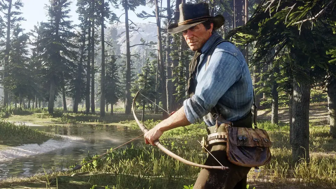 森の川辺で弓を引くアーサー・モーガン。『Red Dead Redemption 2』の公式スクリーンショット