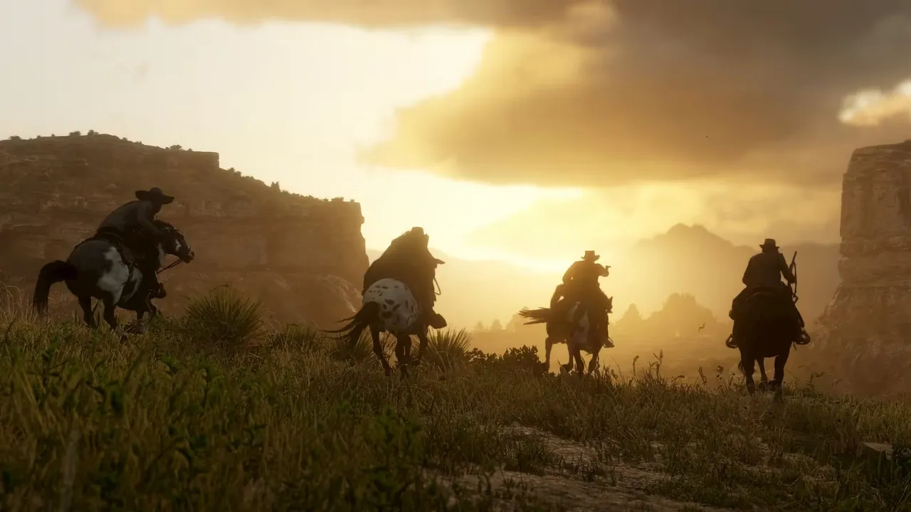 夕日に照らされた荒野を、馬に乗った一団が駆けていく『Red Dead Redemption 2』の公式スクリーンショット